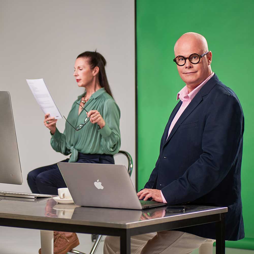 Corporate storytelling video — two presenters work in a professional studio setup with green screen background.